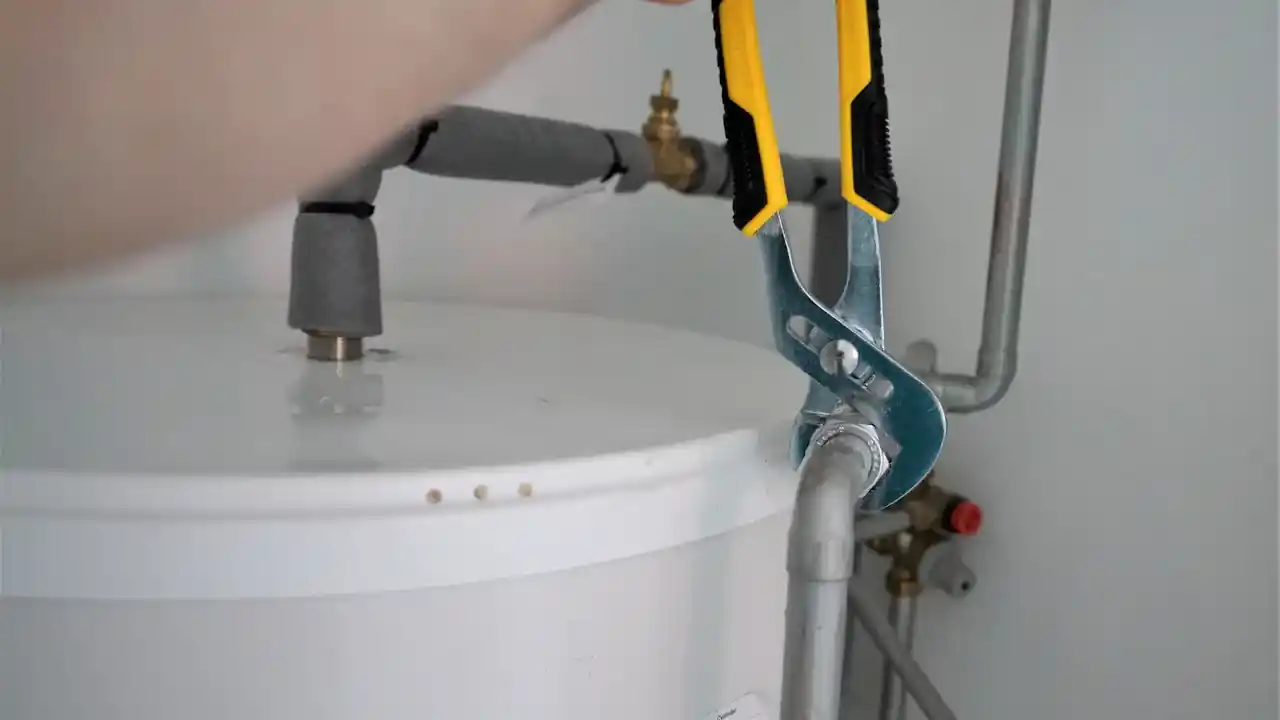Water heater leak repair in La Mirada: plumber tightening a water line on top of a tank